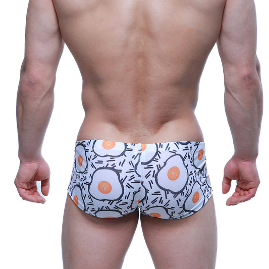 White swim trunks by metromalewear featuring a playful fried egg pattern with orange yolks and black outlines