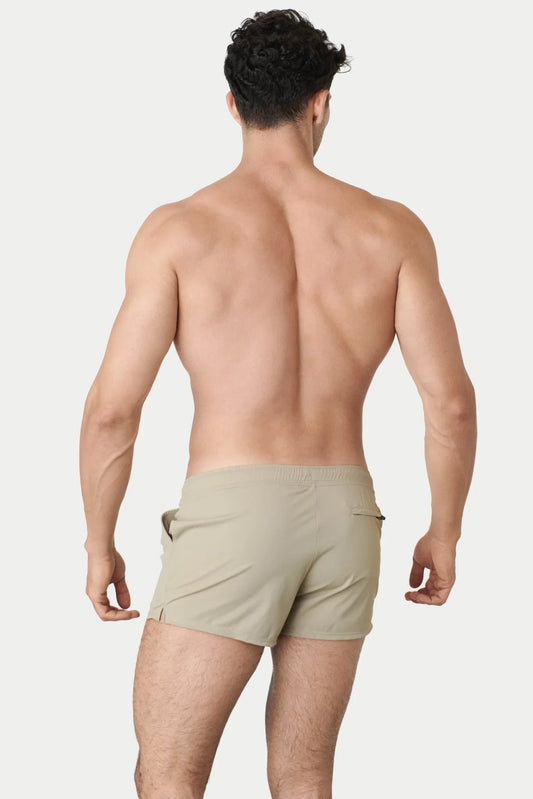 Rear view of a man wearing sand-colored AWRY hybrid swim shorts against a white background.