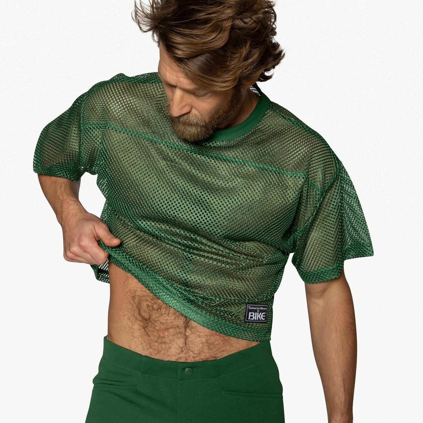 A person wearing a short-sleeve green mesh practice jersey with a small white BIKE logo patch on the lower left.
