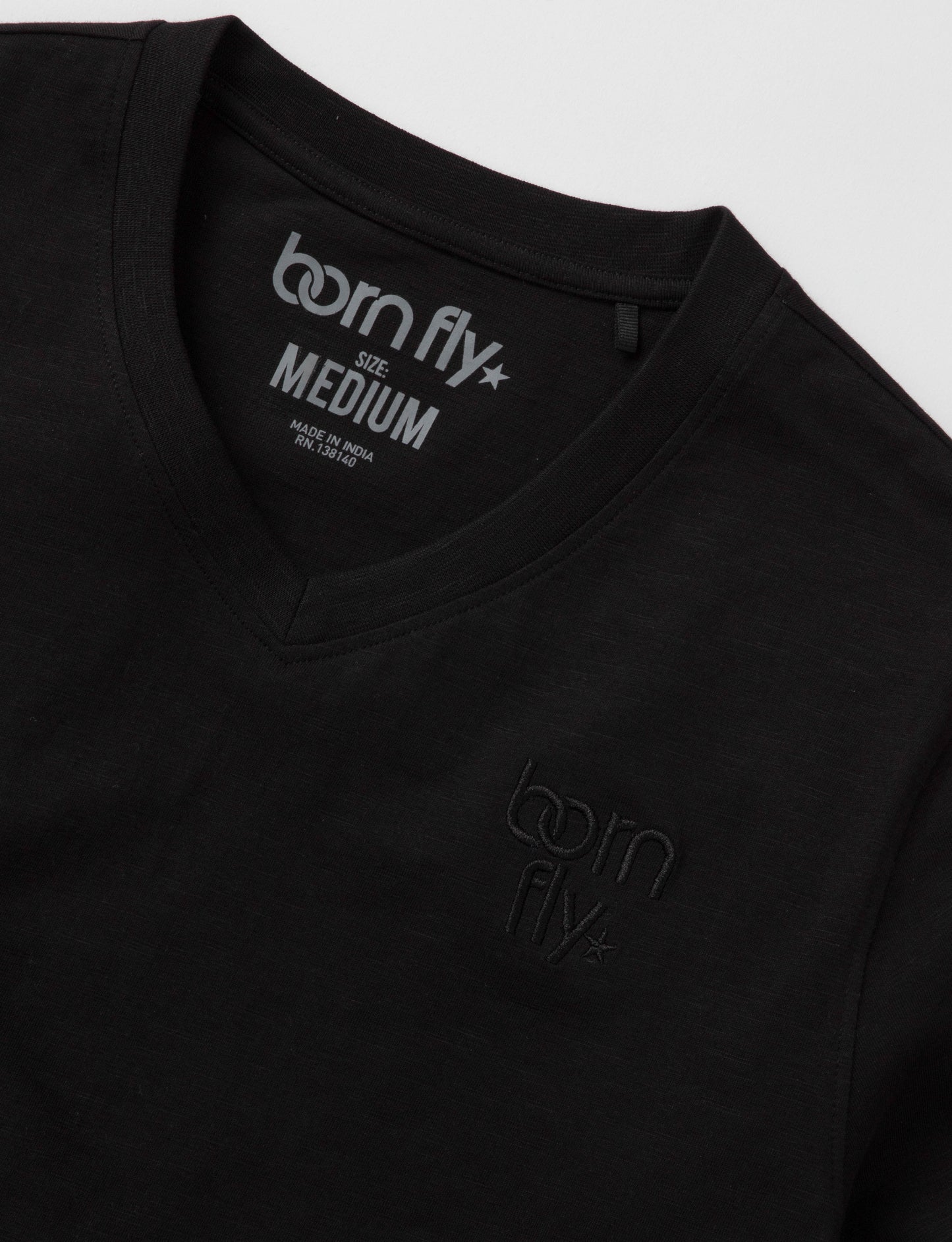 Black cotton born fly v-neck tee with subtle logo embroidery on chest and tagline printed inside collar