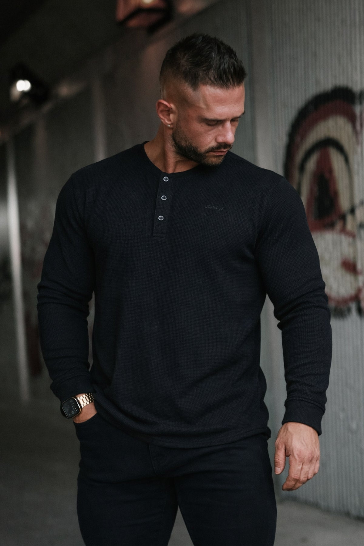 Model wearing a black waffle knit long sleeve henley shirt by Jed North featuring a button placket and fitted design
