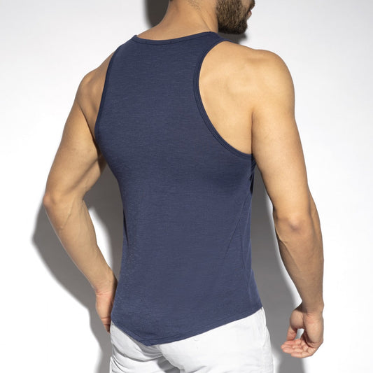 Rear view of a person wearing a navy blue tank top and white trousers against a white background.