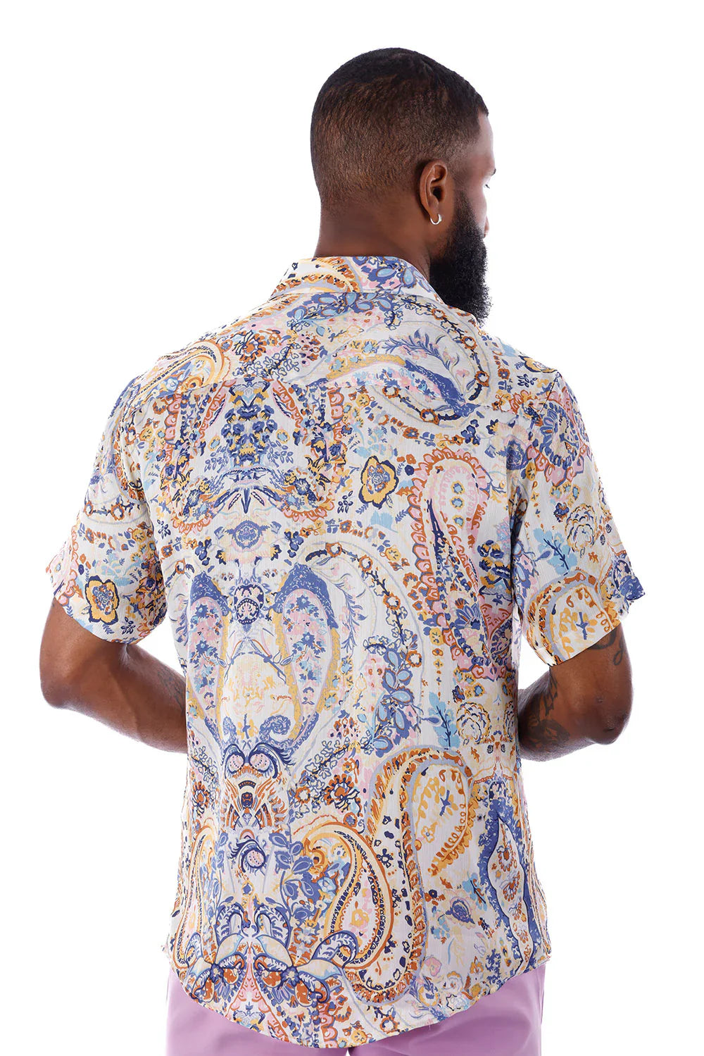 A man wearing an exclusive buzz s/s shirt with a blue gold and cream paisley pattern on a light background