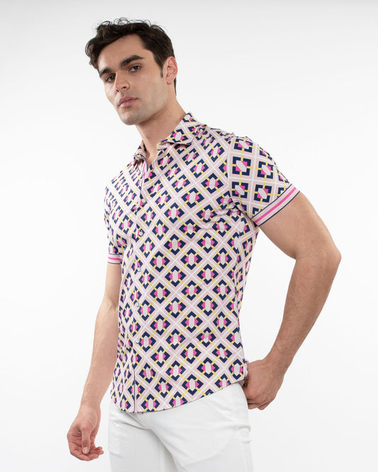 A man wearing a grid parquet printed performance short-sleeved shirt with pink navy blue and cream geometric pattern