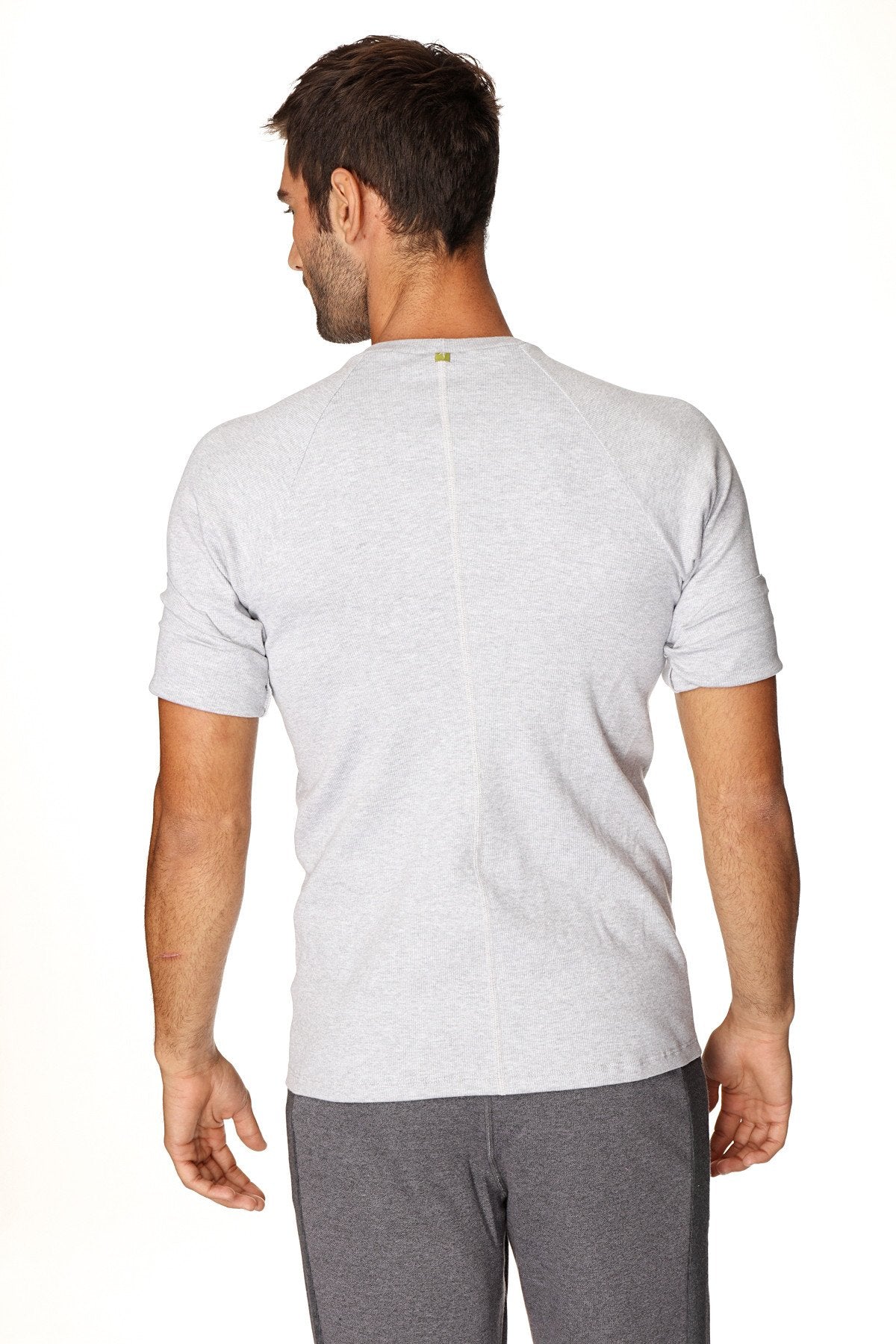 Back view of a gray heathered hybrid crew neck raglan tee with a subtle vertical seam and a small green logo at neckline