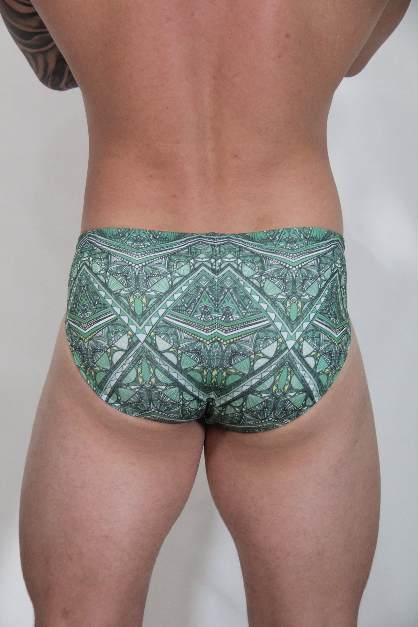 Kaleidoscope swim brief in green patterned fabric with geometric and tribal-inspired designs for swimming use