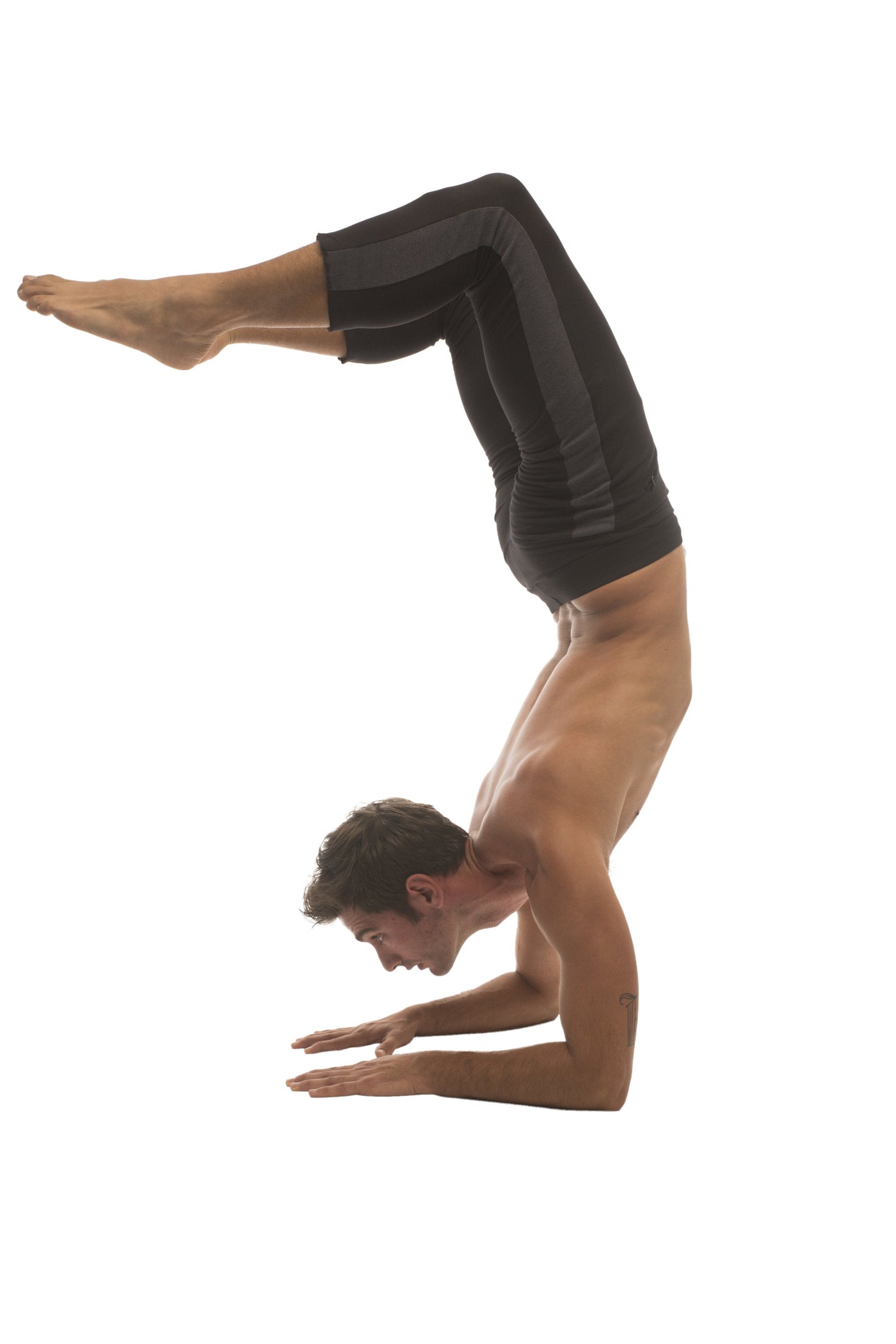 A man performing a handstand wearing black form-fitting mens 4/5 zipper pocket capri yoga pants with charcoal and grey accents
