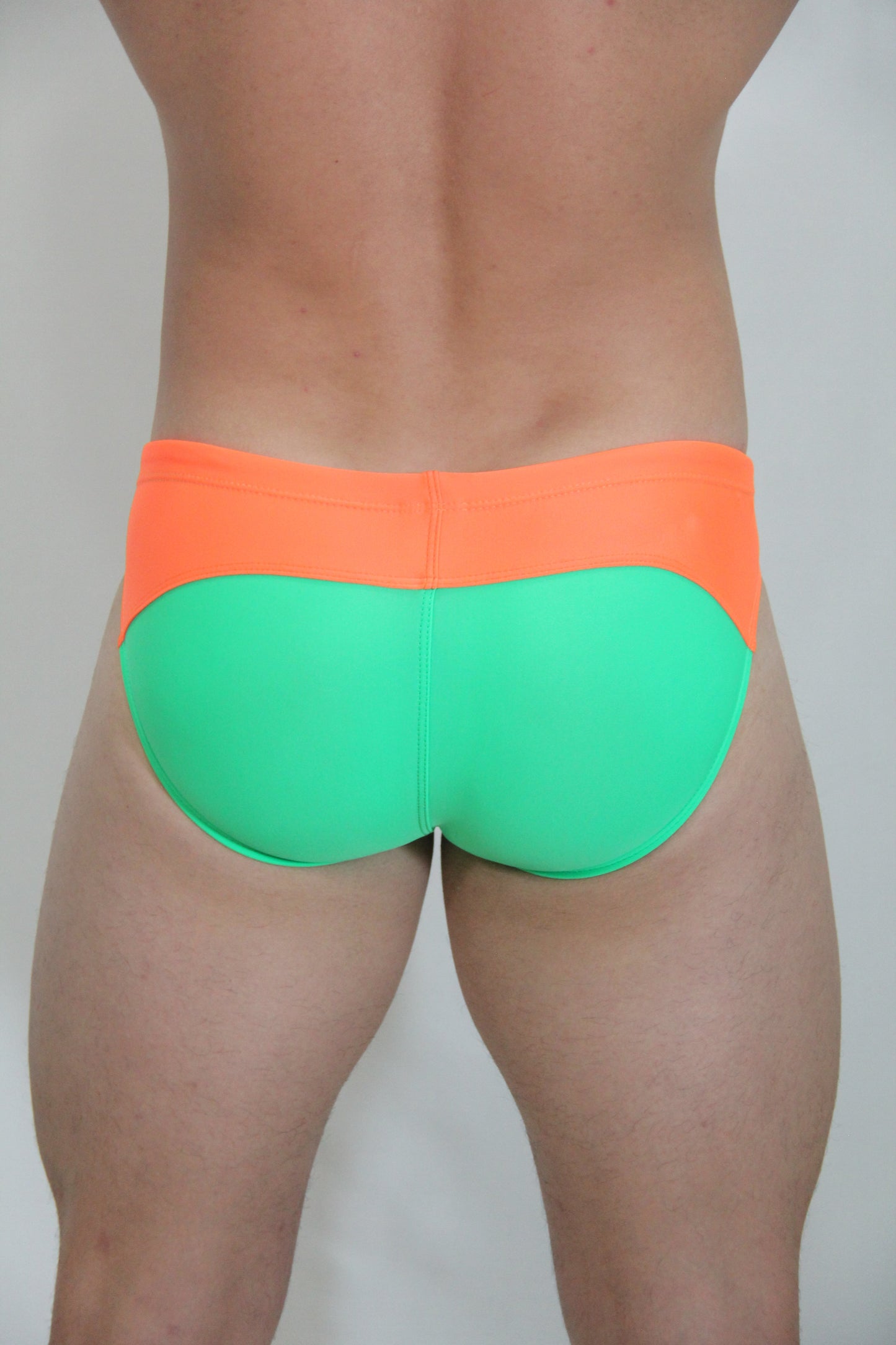 Neon curved swim brief in bright orange and neon green two-tone design perfect for vibrant swimwear style