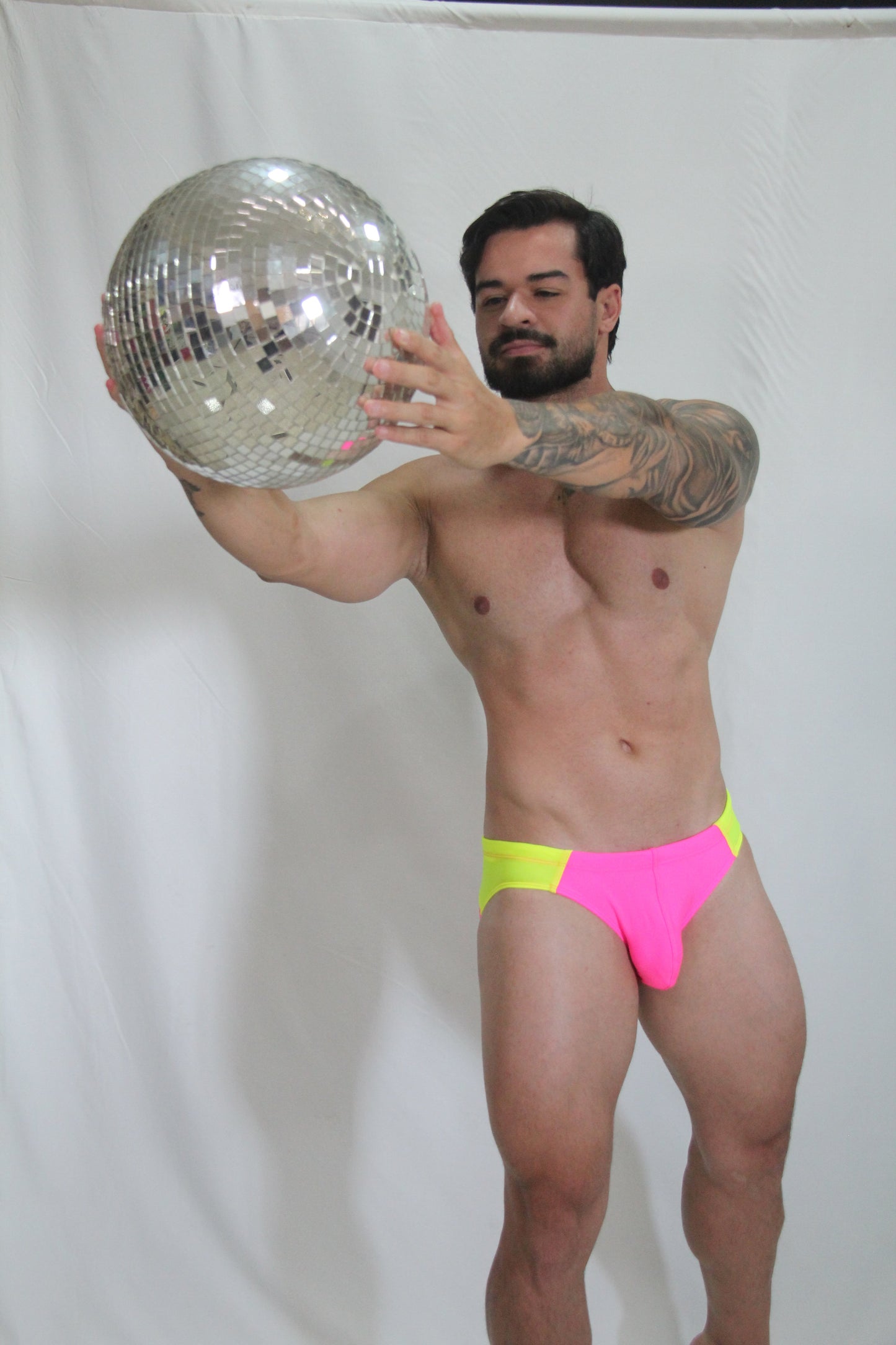 Shiny silver disco ball with mirrored facets reflecting light for neon curved swim brief product display