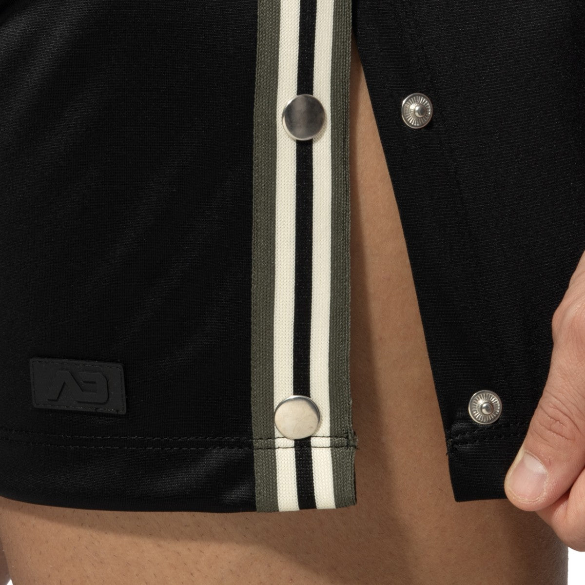 Black varsity jacket with olive and white striped placket and silver snap buttons shown with nexus button shorts