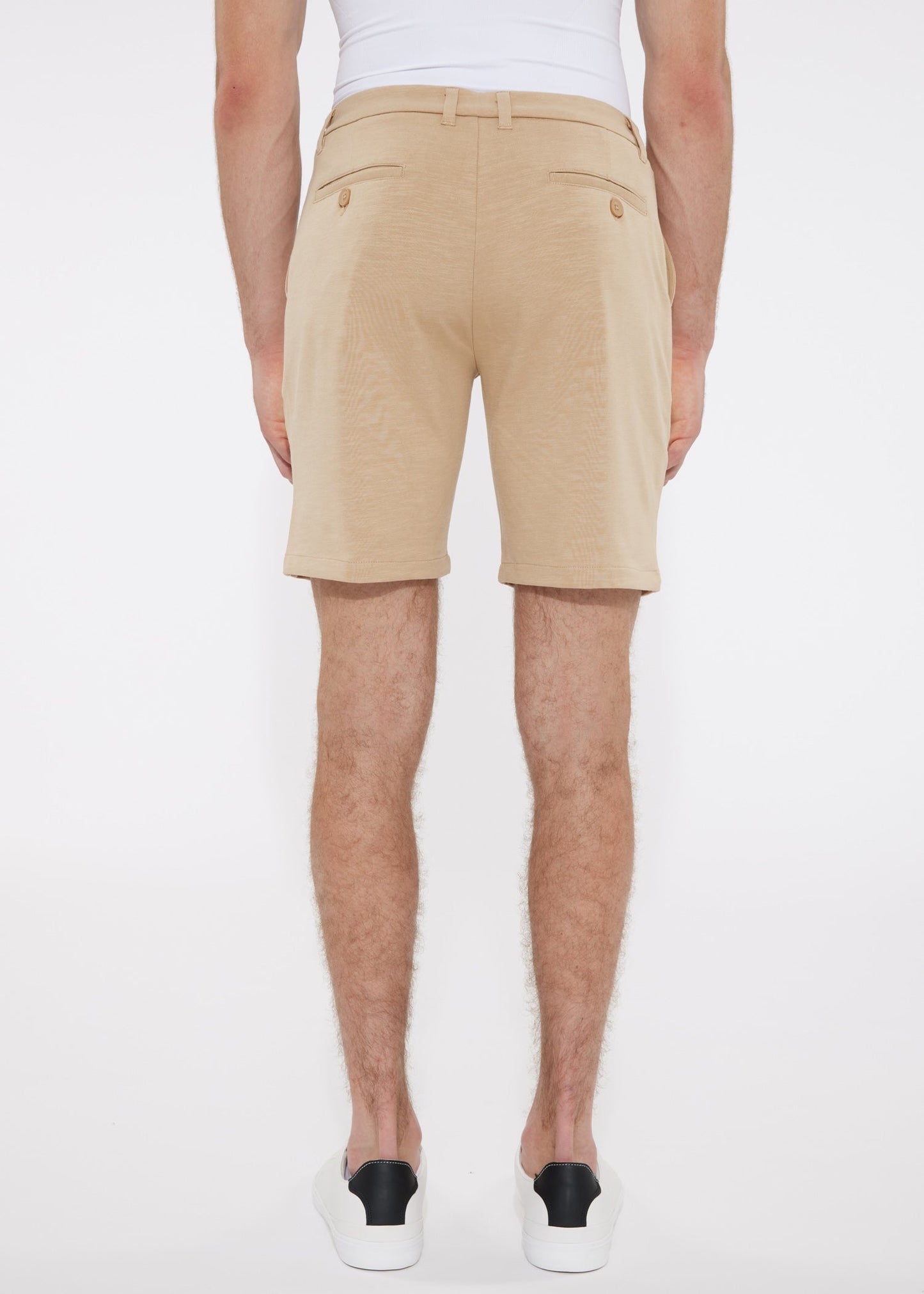 Beige solid stretch knit chino shorts with tailored fit and buttoned back pockets shown from the back side