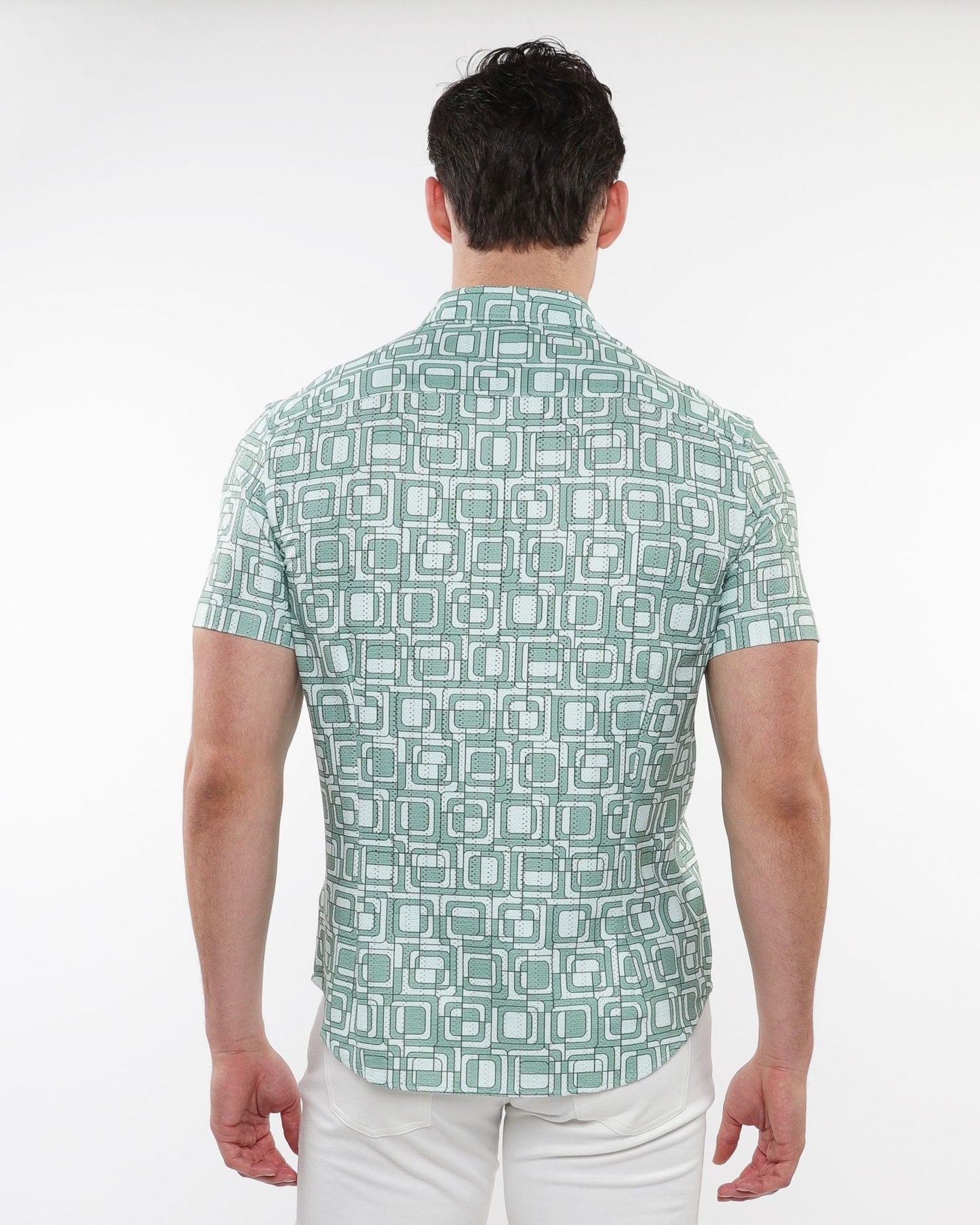 A man wearing a light green short-sleeved squares print open knit shirt with white and dark green geometric patterns