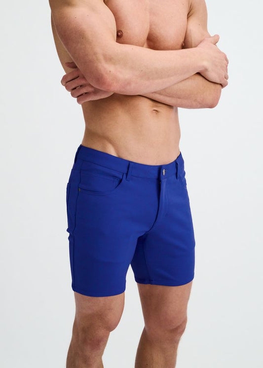 A person wearing slim-fit, blue stretch knit shorts with belt loops and front pockets against a white background.