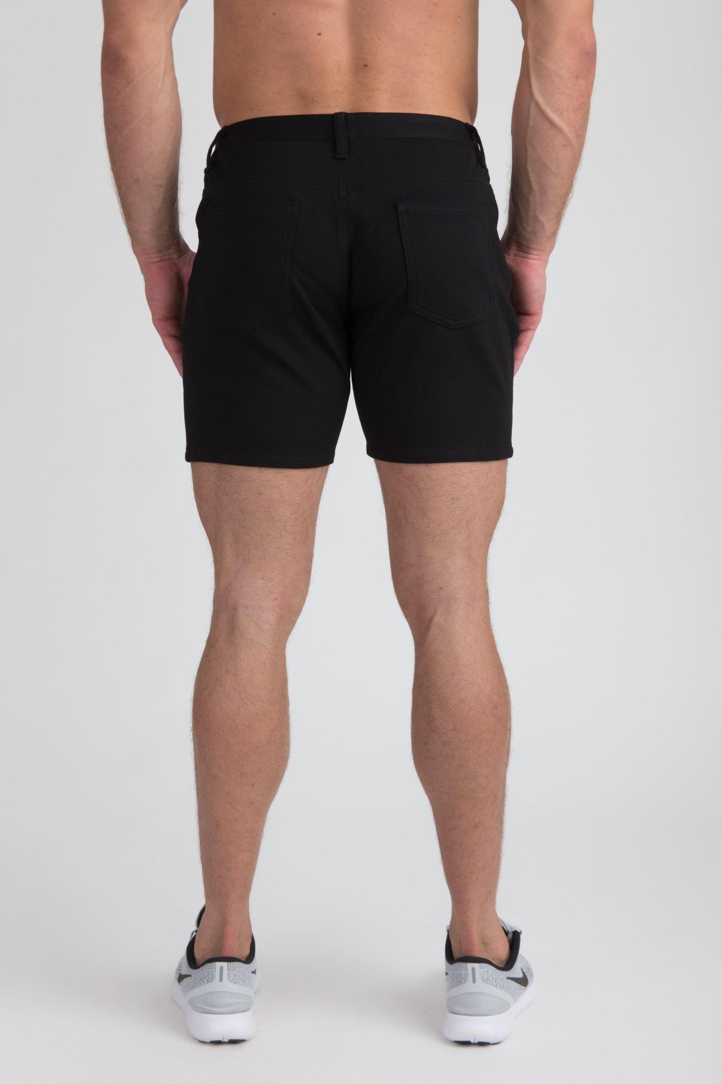 Black stretch knit short with tailored fit and two rear pockets shown from the back side