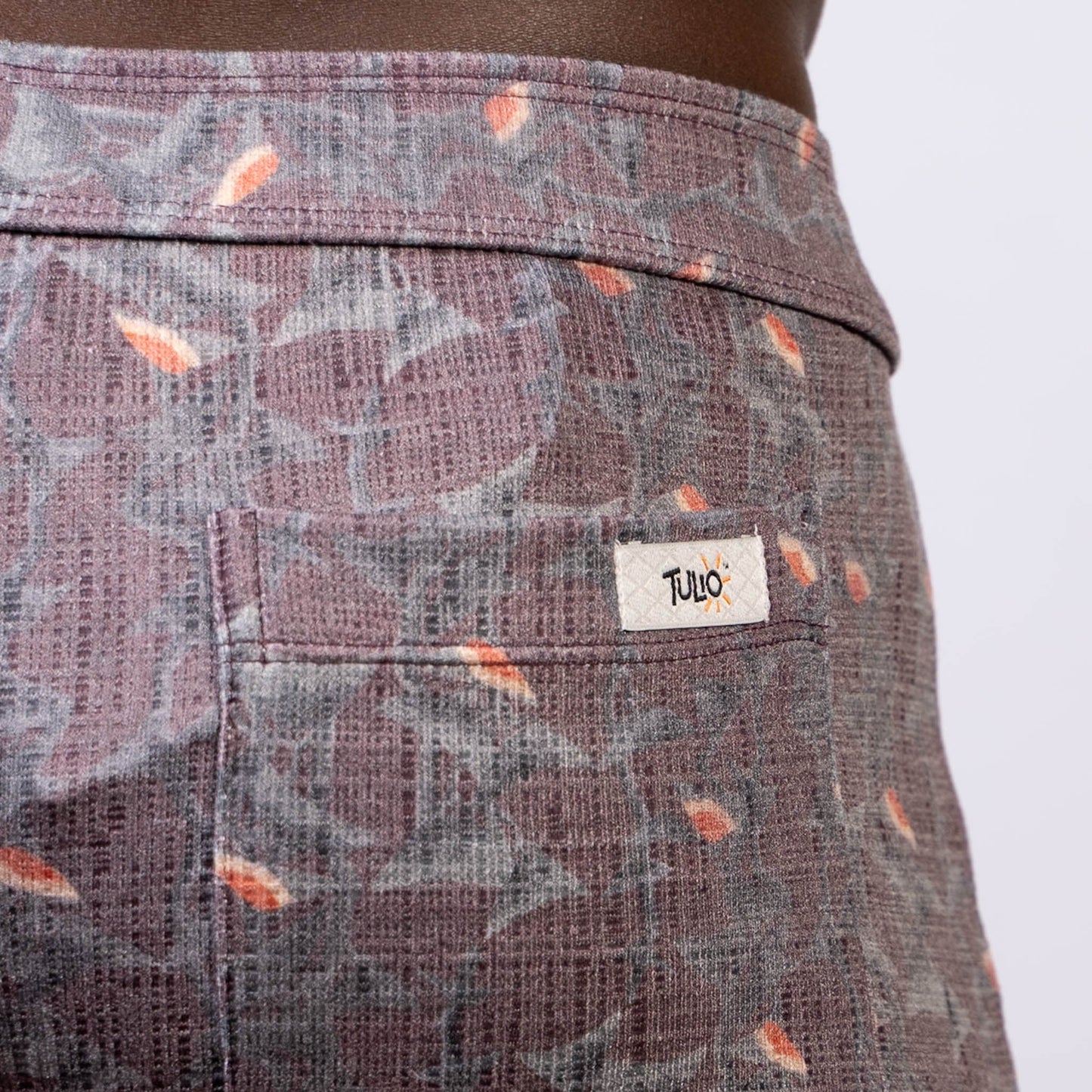 Back side of vintage stripes linen texture shorts in purple and gray with orange leaf accents and tulo label on pocket