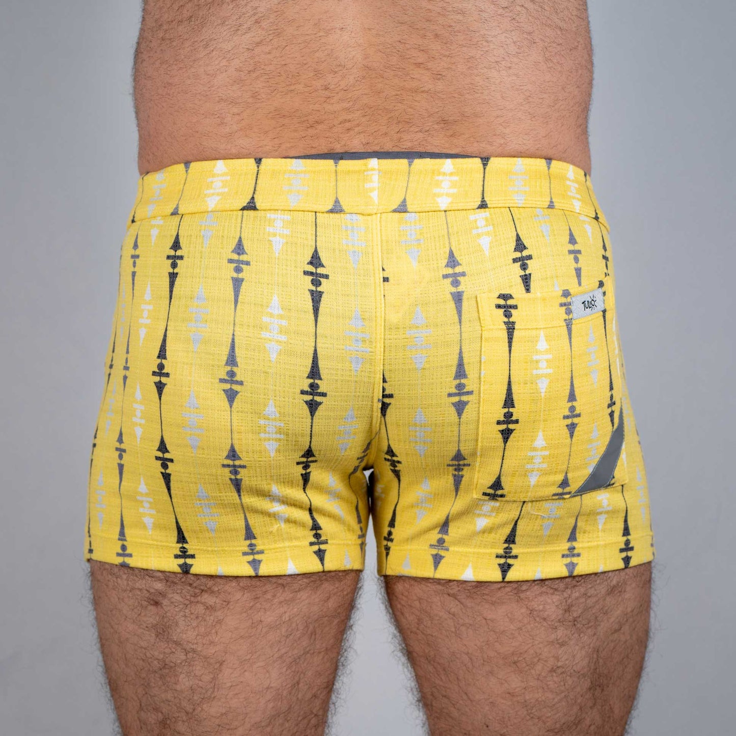 Bright yellow wallpaper print linen texture shorts with bold black and white geometric pattern and branded back pocket tag