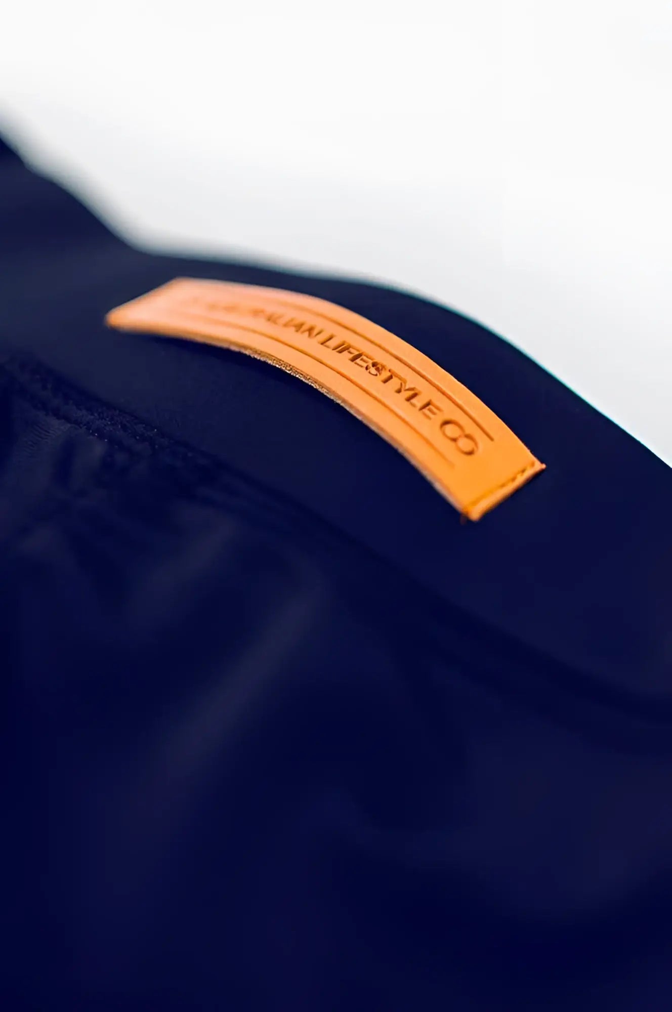 A tan leather lifestyle co patch embossed in black sewn on dark navy fabric of bondi short back side