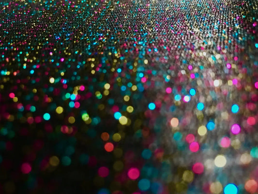 A glitter mesh tank featuring a vibrant multicolored glitter surface with pink blue gold and teal shimmering particles