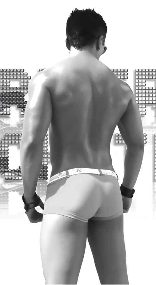 Black and white image of a muscular man wearing icker sea sailor belted logo square cut trunk swimwear in red and white