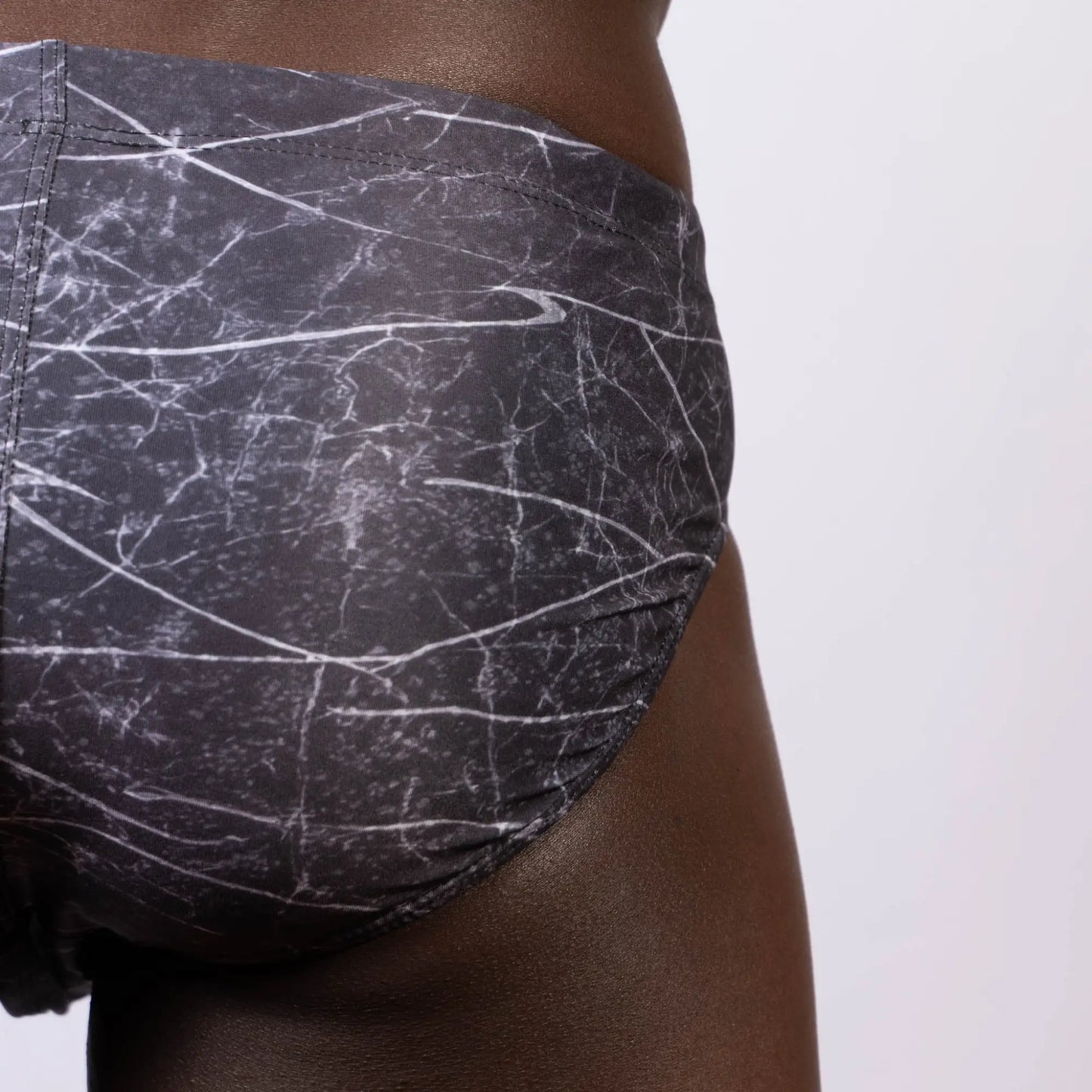 Black and white marble-patterned men’s lightning swim brief with subtle Nike swoosh logo designed for swim use