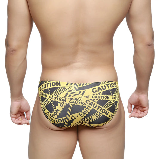 MetroMaleWear caution lowrise bikini swim trunks in black with yellow and black caution tape pattern front view