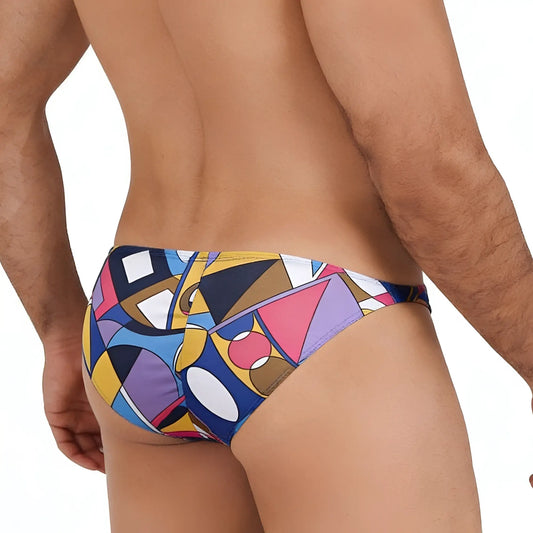 MetroMalewear Picasso swim trunks featuring a vibrant geometric pattern in bold blues, yellows, pinks, and purples.