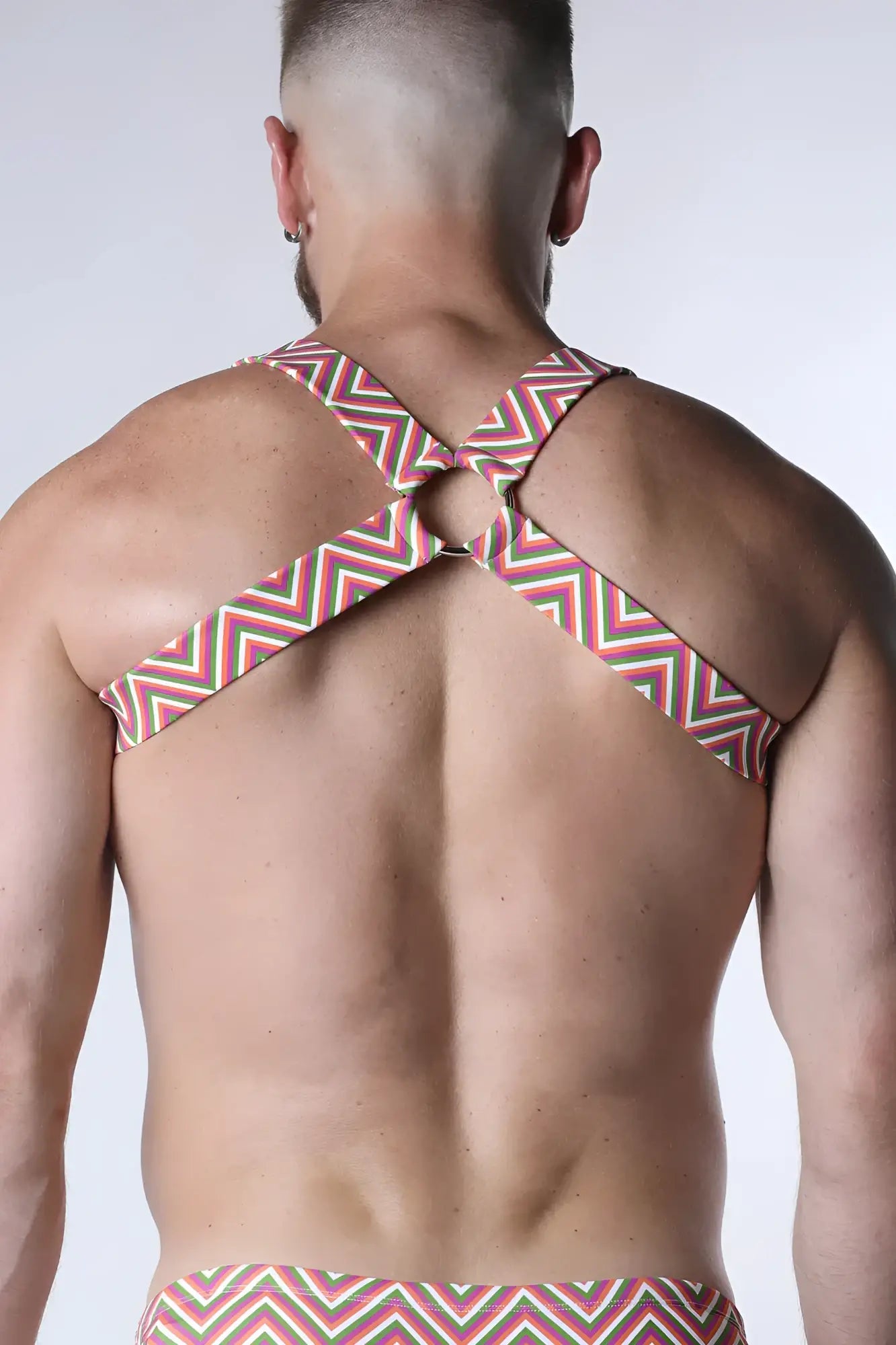 A man wearing the back side of a pulse elastic harness in red white and green zigzag pattern with crossed straps