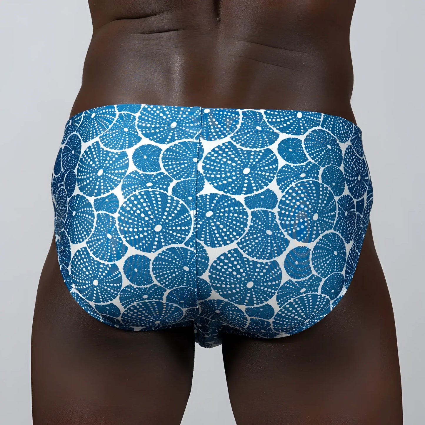 Blue and white patterned sand dollar brief swim trunks featuring circular sea urchin motifs for beachwear