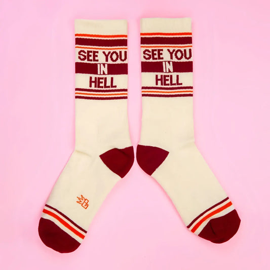 Cream-colored SEE YOU IN HELL crew socks with maroon and orange stripes and bold red lettering across the top