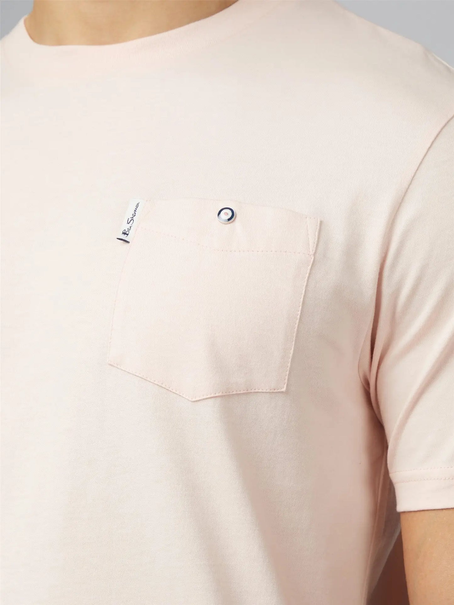 A soft blush pink signature t shirt with short sleeves chest pocket silver button and small branded tag