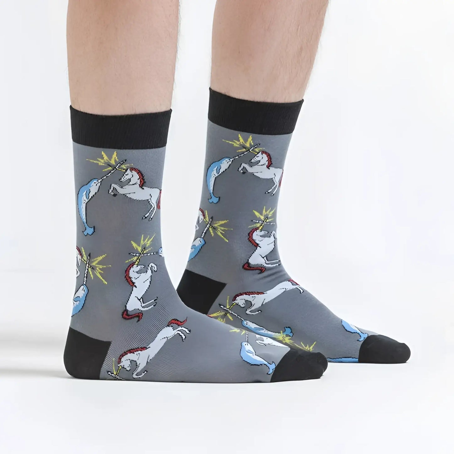 Gray socks with black cuffs and toe caps featuring playful white unicorns and blue narwhals in whimsical battles