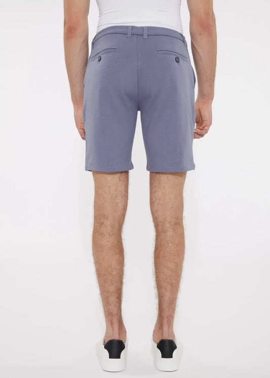 A pair of men’s solid stretch knit shorts in soft lavender with smooth lightweight fabric and dark button accents on back pockets