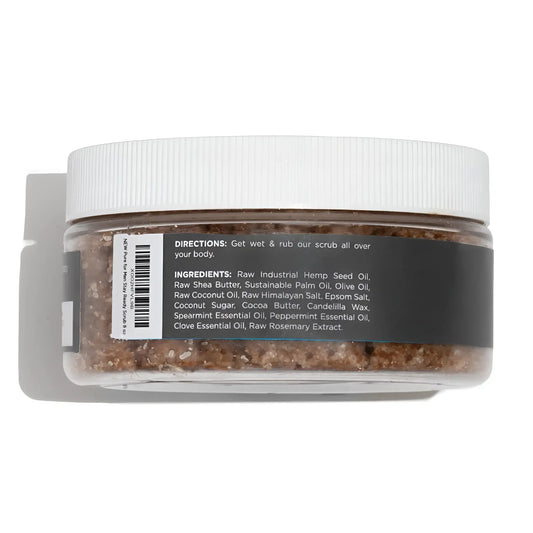 A clear plastic jar with white ribbed lid contains brown granular body scrub stay ready scrub with ingredient label