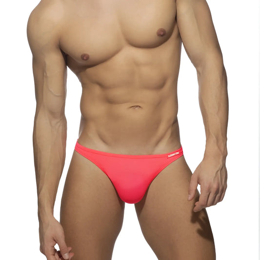 Bright pink form-fitting swimwear g-string swim trunks with a subtle brand logo on the waistband front side
