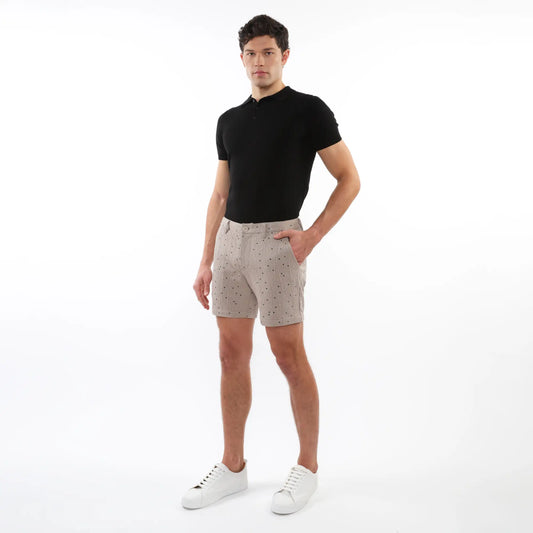 Beige textured jacquard stretch chino shorts with subtle dark dot pattern worn by a model in casual summer attire