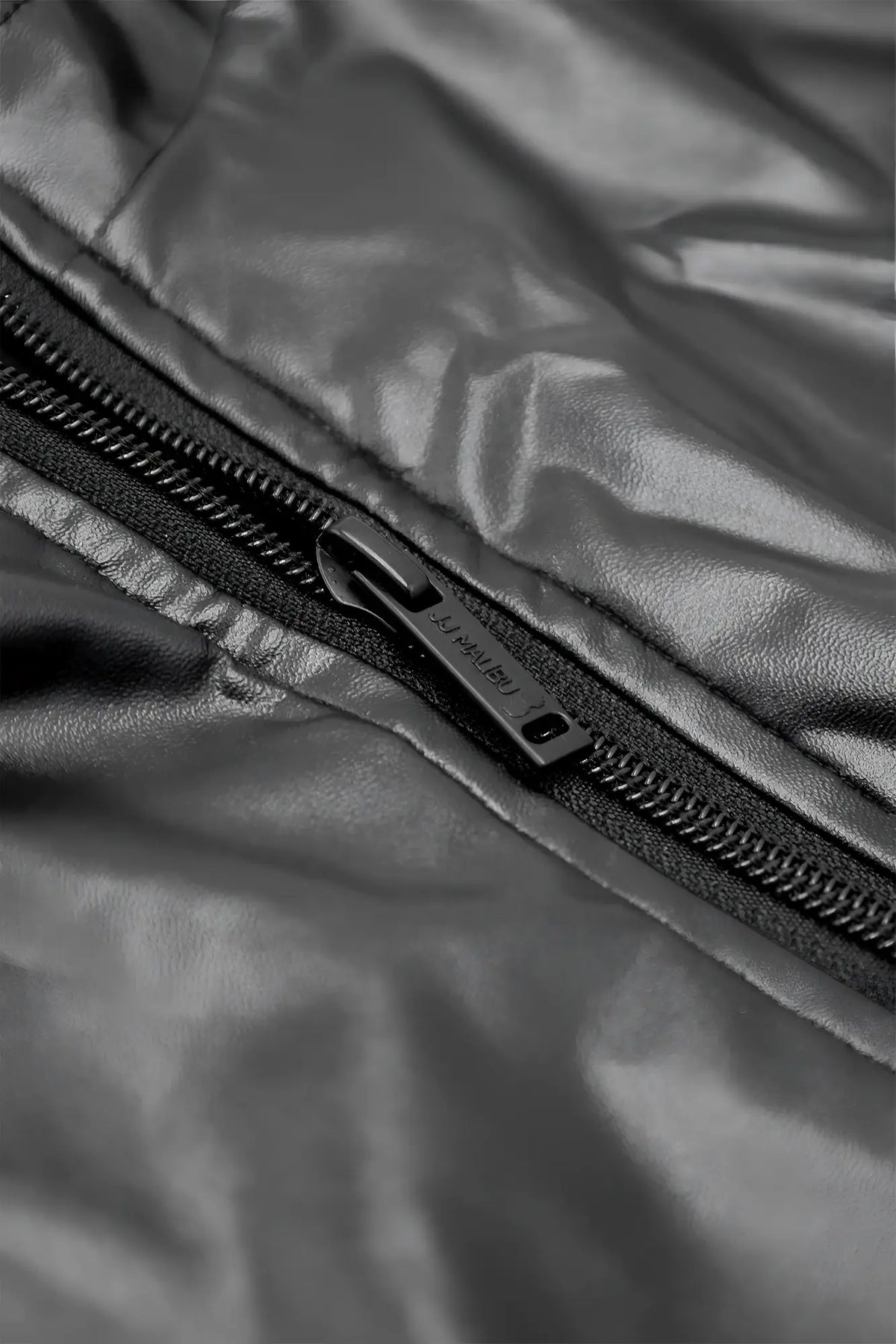 Black vegan leather zipper bodysuit featuring a sleek metallic pull tab on a shiny quilted jacket panel