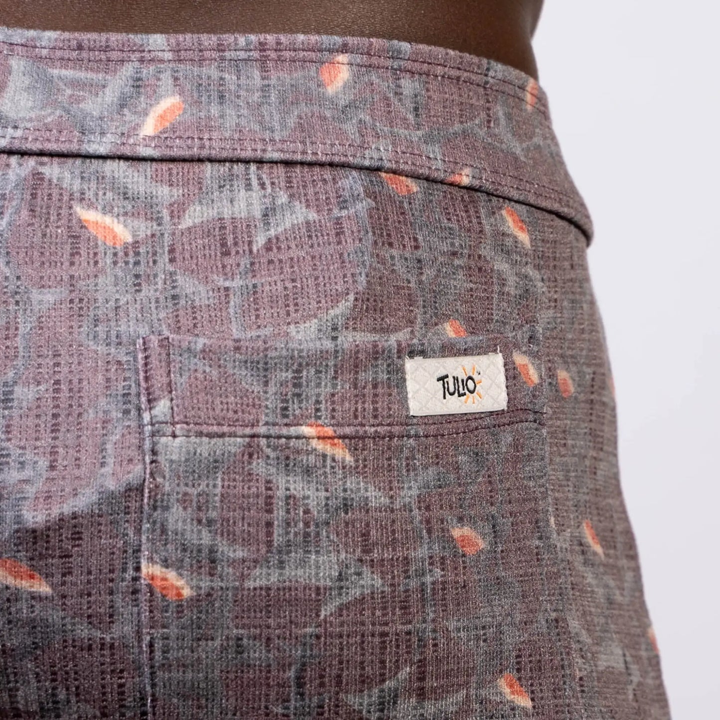 Back side of vintage stripes linen texture shorts in purple and gray with orange leaf accents and tulo label on pocket