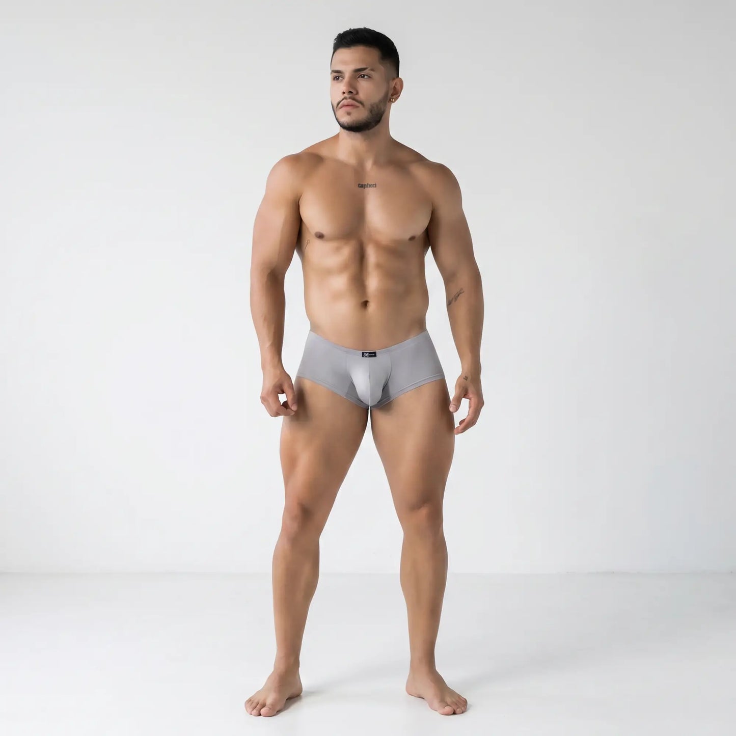 Athletic male model wearing Xtremen 91219 gray microfiber trunks in a minimalist studio, sleek form-fitting design
