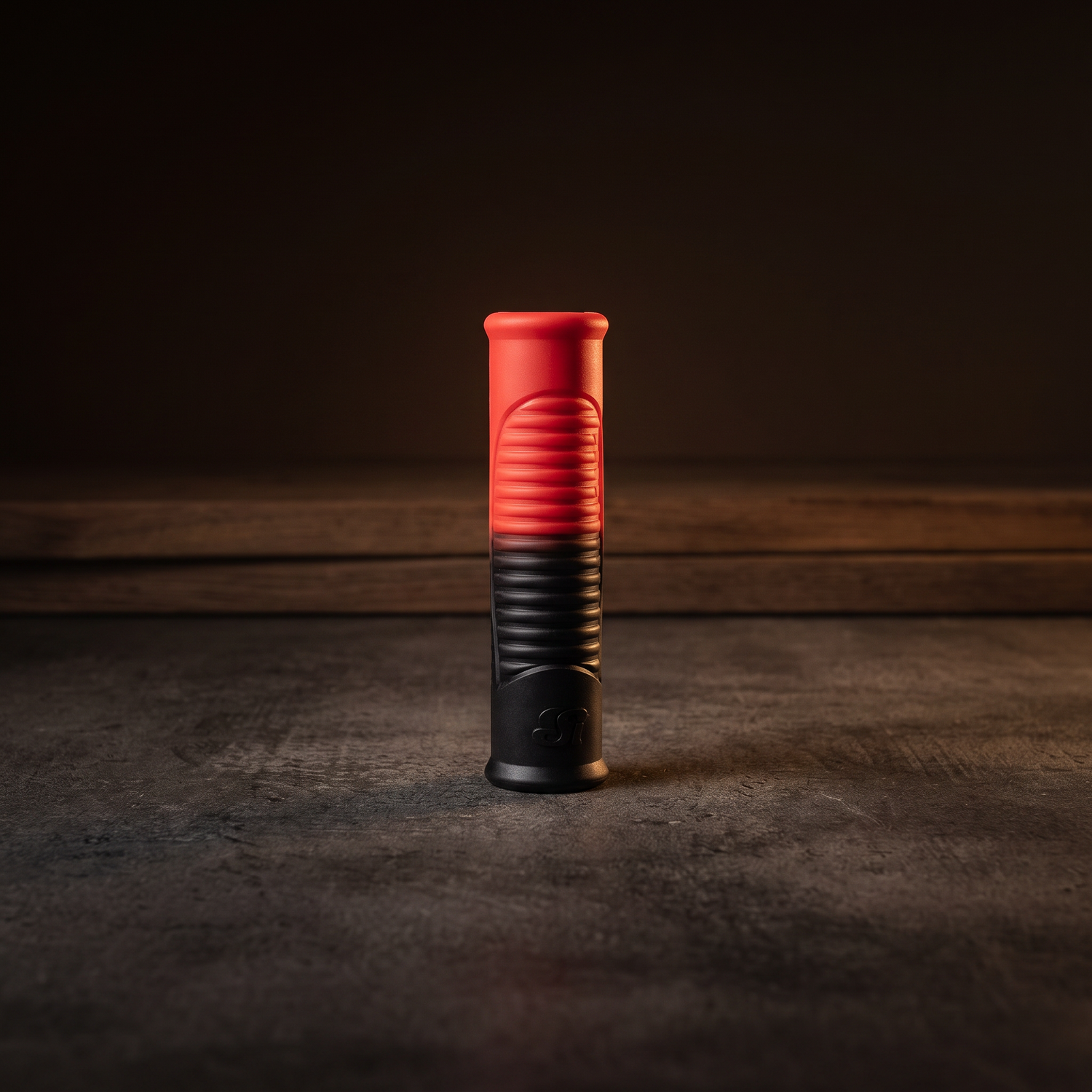 Si Novelties Pole To Pole Docking Sleeve in red and black ribbed silicone, displayed on a wet dark surface against a moody charcoal studio backdrop
