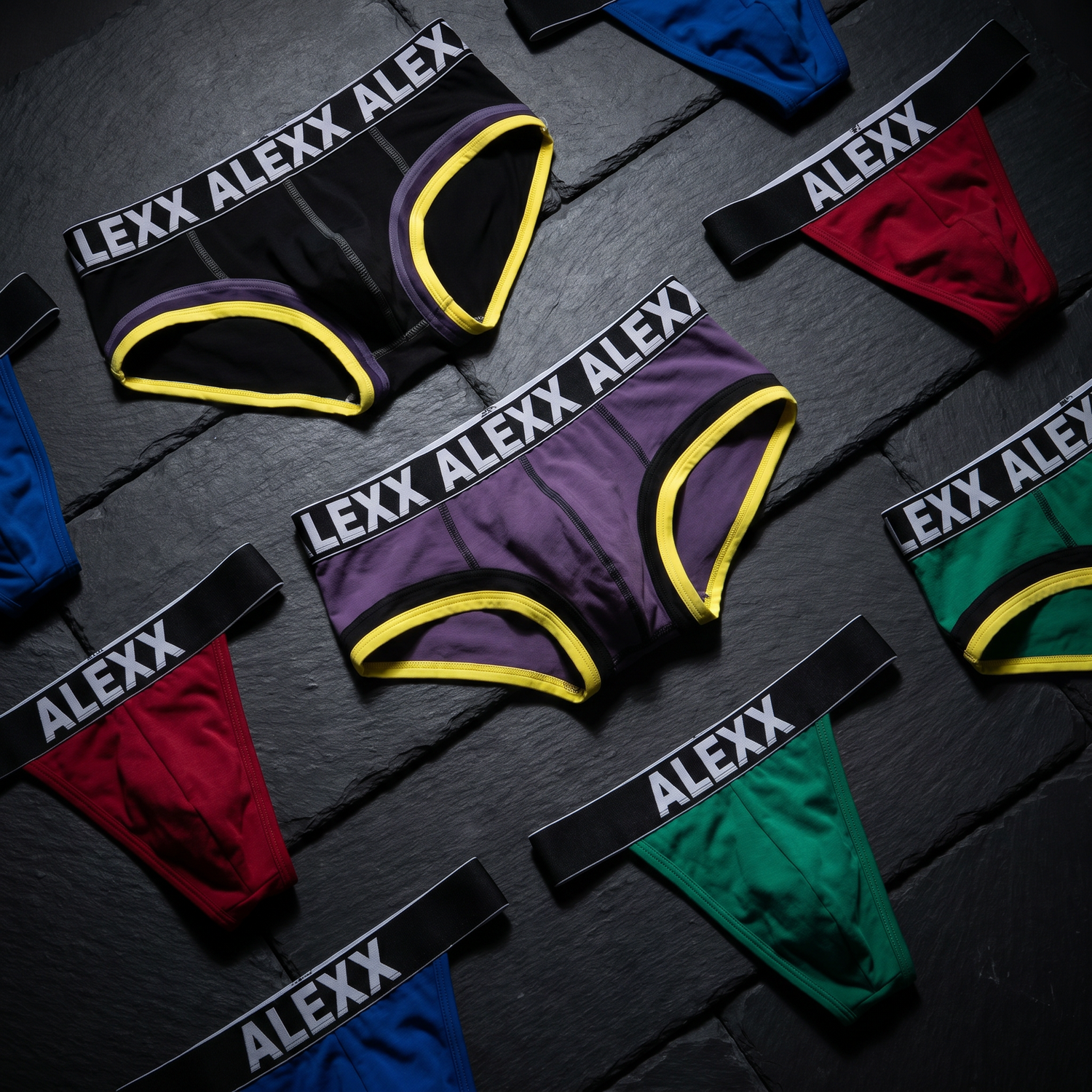 Alexx underwear collection editorial flat lay with bold branded briefs on dark surface