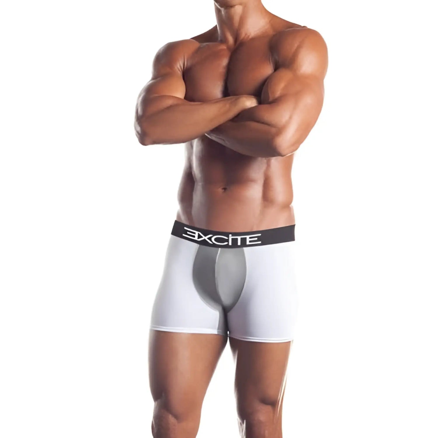Muscular man stands with arms crossed wearing white boxer briefs against white.