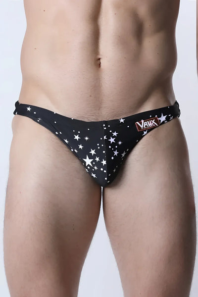 Black bikini-cut briefs with white star print on a standing male model.