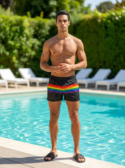 Shirtless man in black mesh shorts with rainbow stripe poolside at daytime.