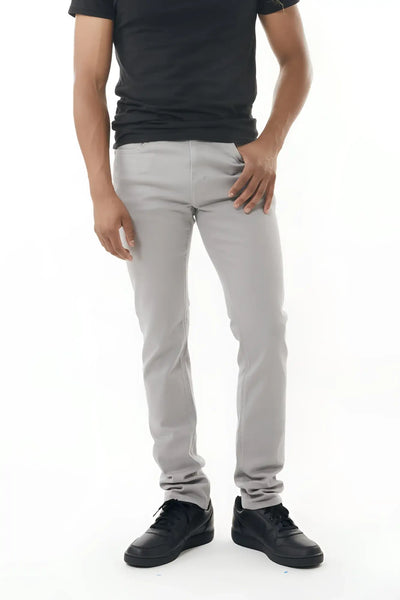 Man in black shirt and gray pants standing against white background.