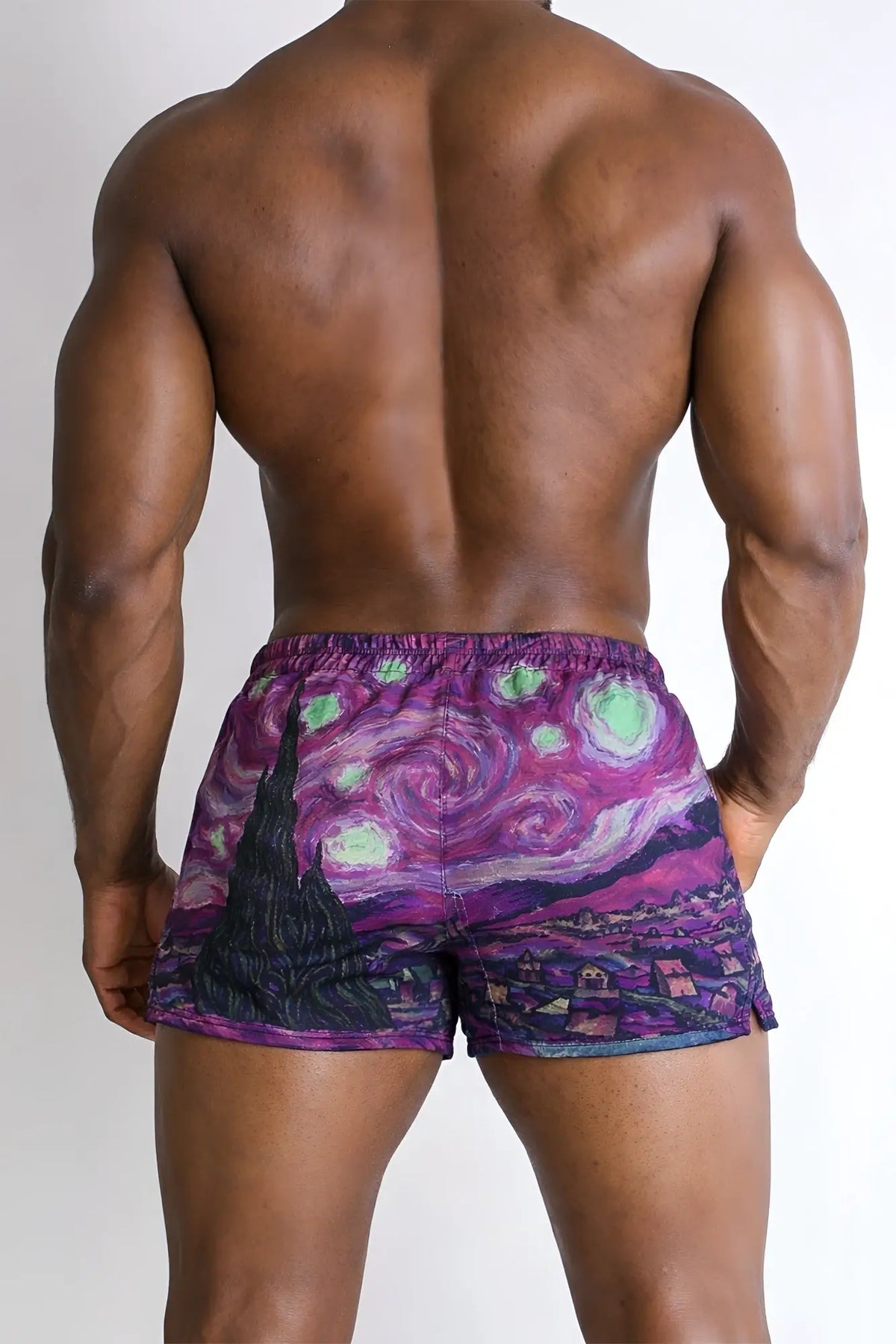 Purple 2 inch side split booty shorts with vibrant swirling night sky design and glowing green stars back shown