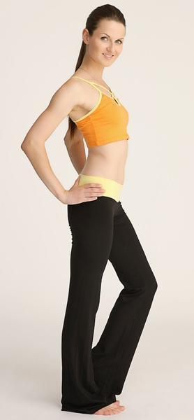 A woman wearing 4-rth women’s classic yoga pant in black flared leggings and a vibrant orange sports bra with yellow trim