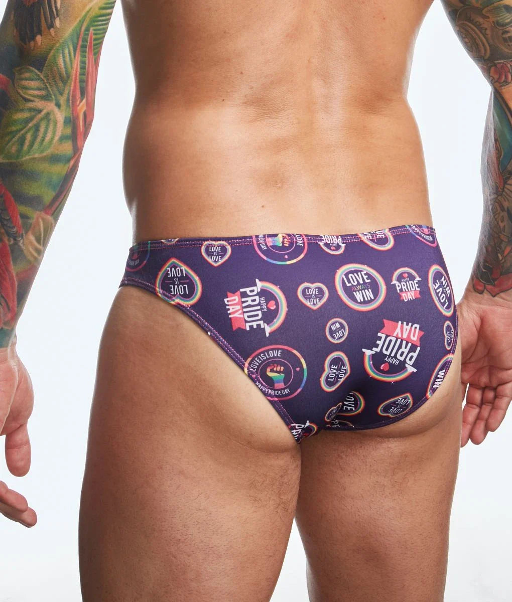 Purple swim trunks with vibrant rainbow pride day logos and text by justin + simon classic mens bikini fun prints
