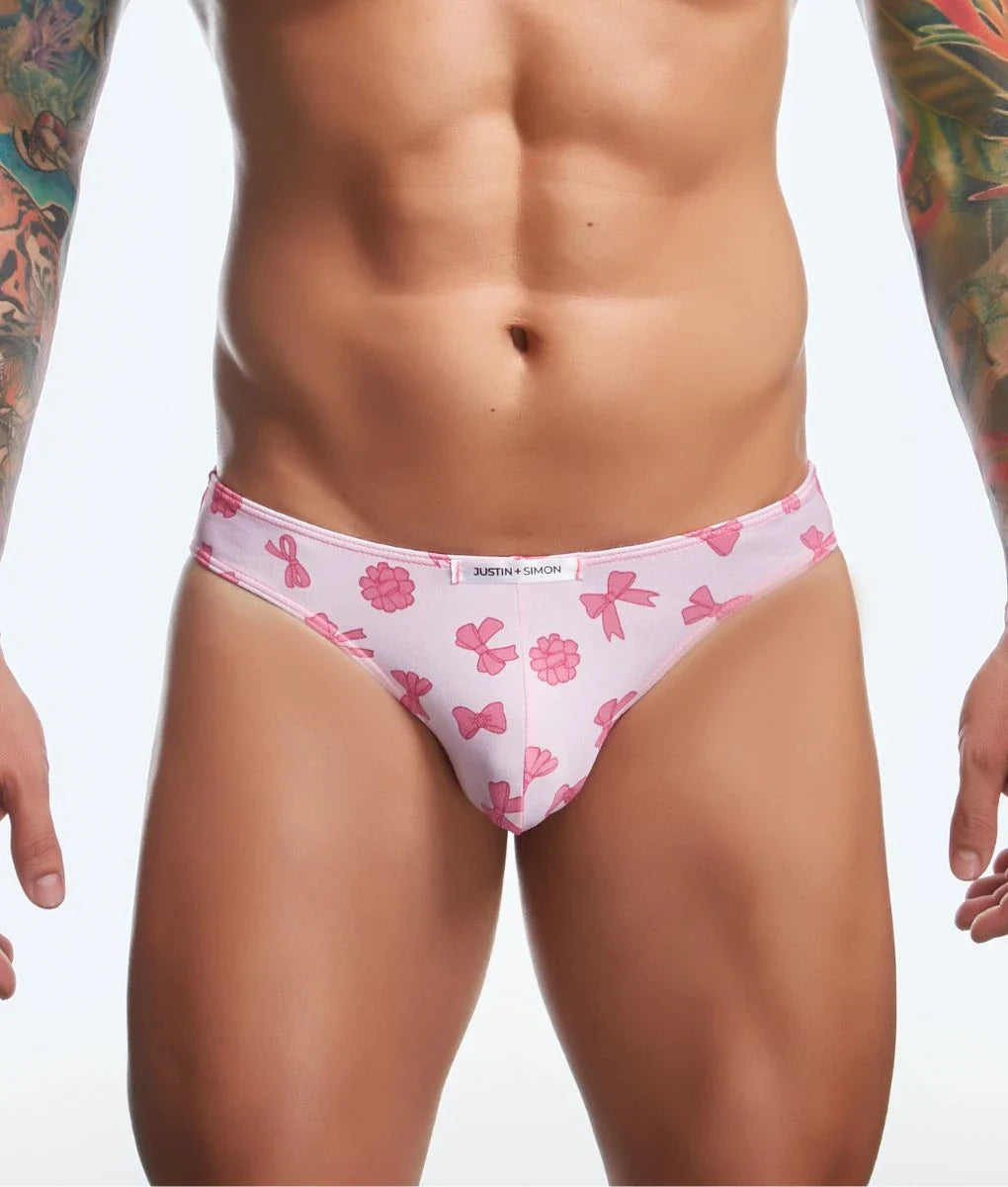 Pink patterned briefs with bow and flower designs and white brand tag from justin + simon classic mens bikini fun prints