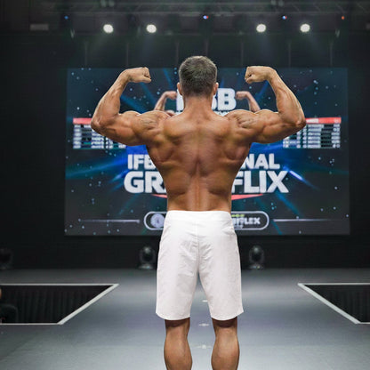 A muscular man wearing white metro male wear physique board short corona 4706-36 shows defined back muscles