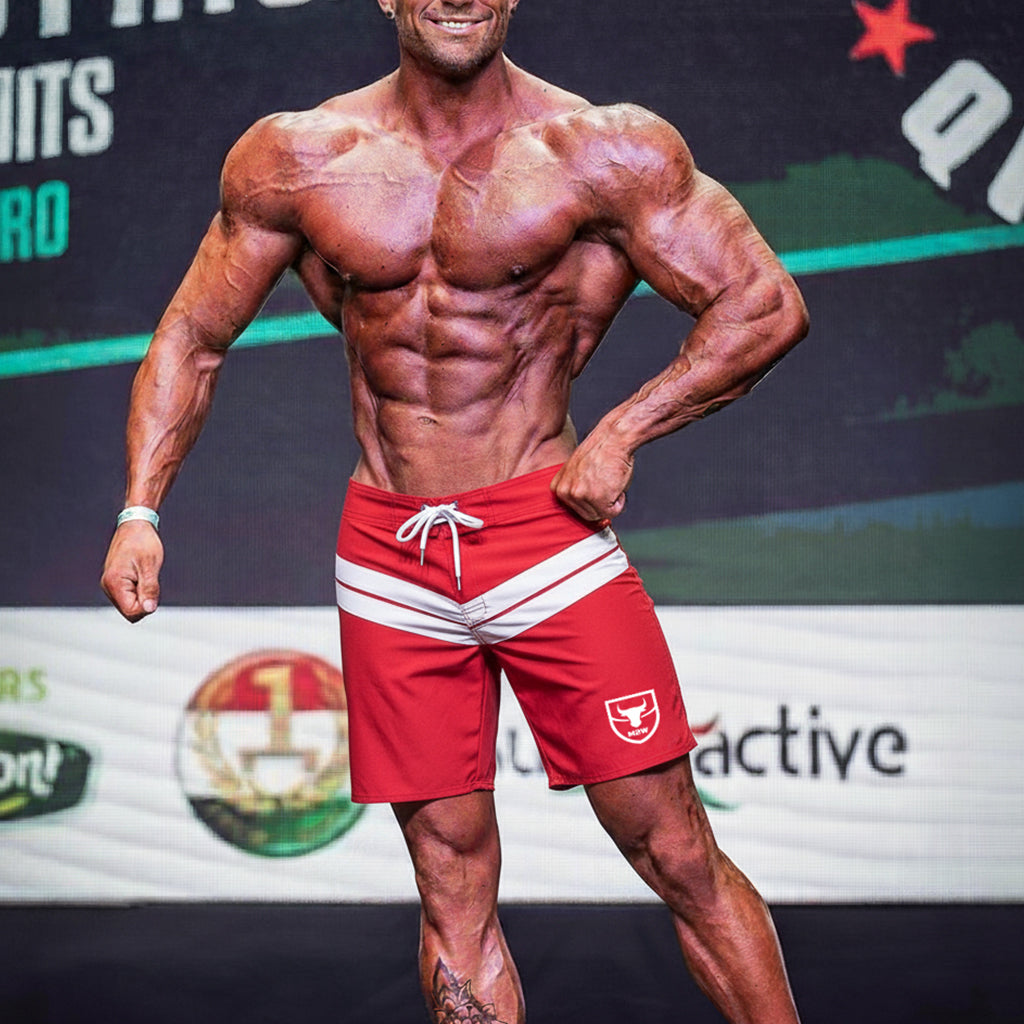Red athletic board shorts with white stripes and a small bull logo on the left leg by metromalewear